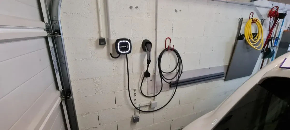 Borne de recharge installée sur un mur de garage avec cheminement de câble soigné